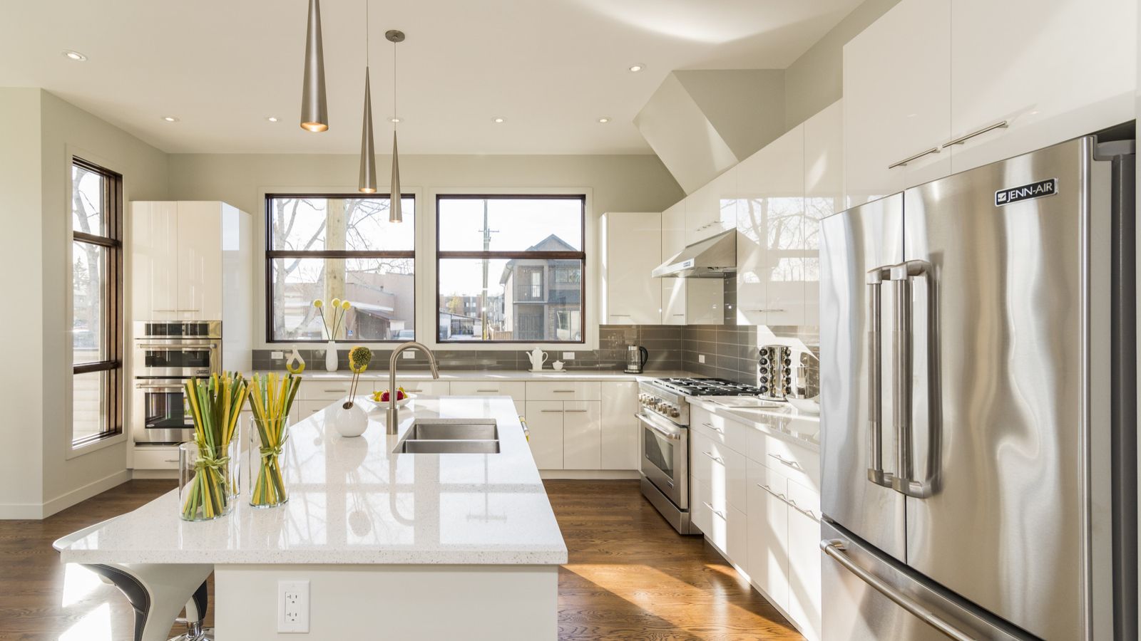 Bright modern white kitchen with large island and stainless steel appliances