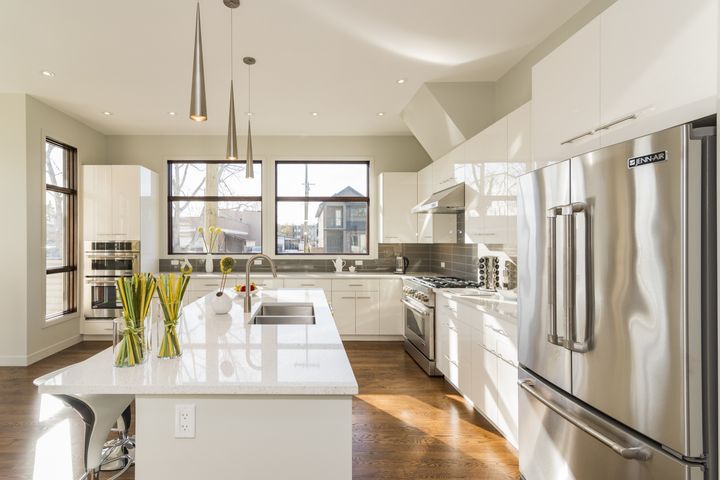 Bright modern white kitchen with large island and stainless steel appliances