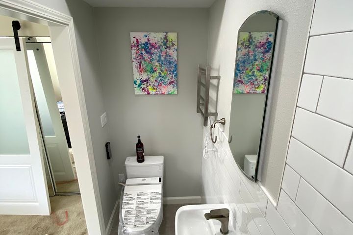 Powder room with white vanity, toilet, artwork, and twin mirrors