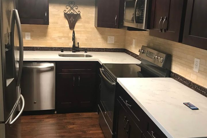 Compact remodeled kitchen with dark cabinets and stainless steel appliances