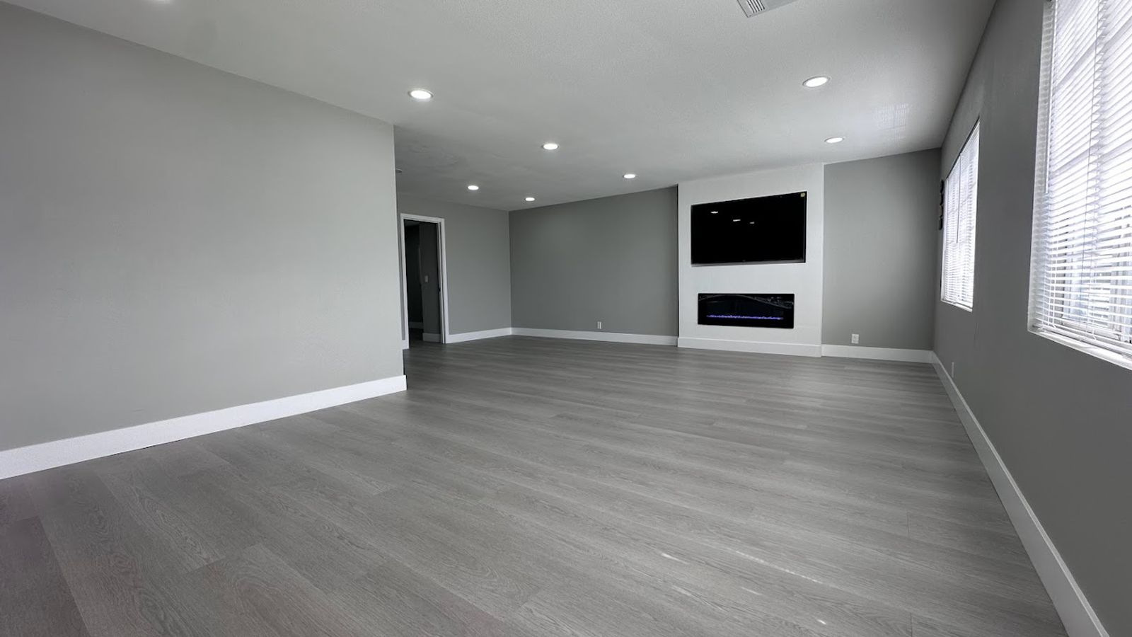 Renovated living room with gray flooring, recessed lights, and fireplace