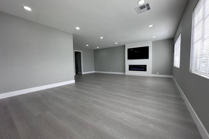 Renovated living room with gray flooring, recessed lights, and fireplace
