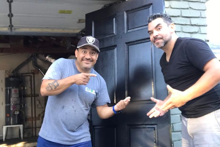 Two remodeling crew members carrying a black entry door